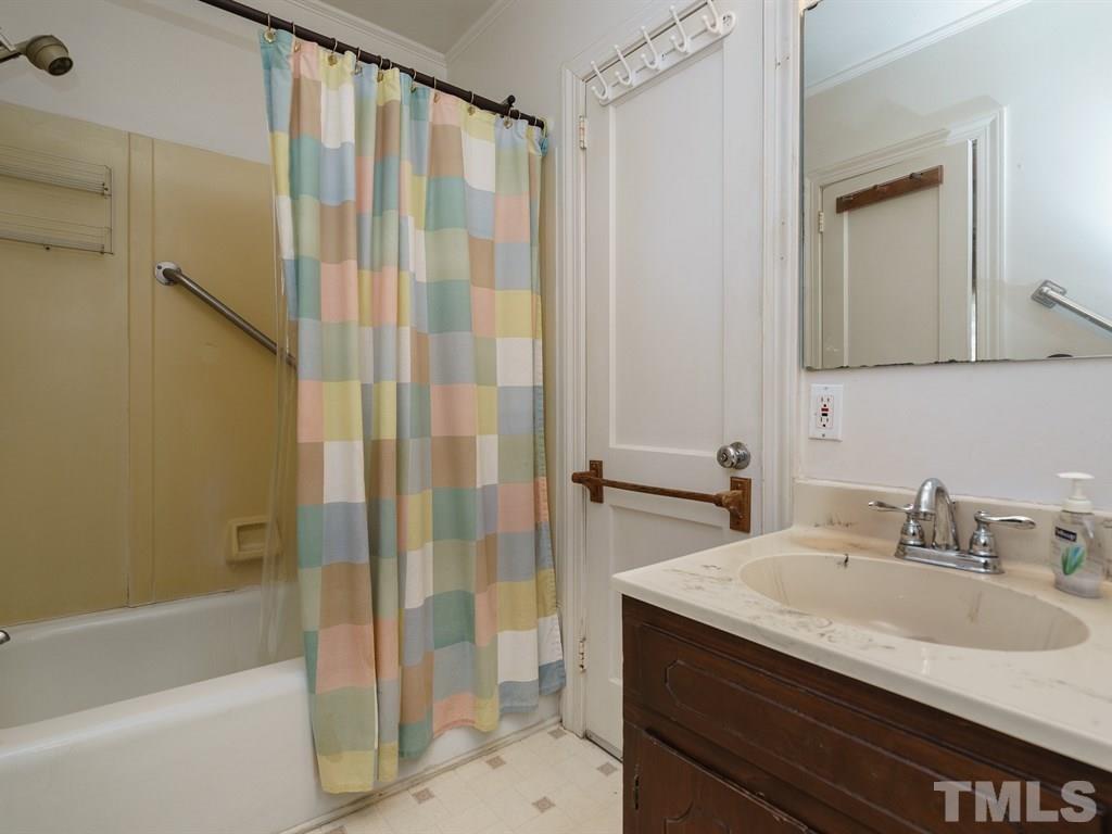 713 Kimbrough Street Raleigh, NC 27608 - Photo 15 of 25 a bathroom with a granite countertop sink a mirror a vanity and a bathtub