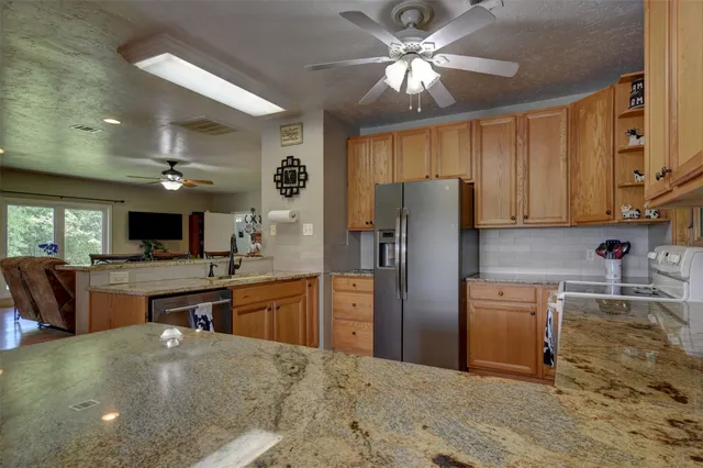 a large kitchen with stainless steel appliances granite countertop a sink and a wooden floors