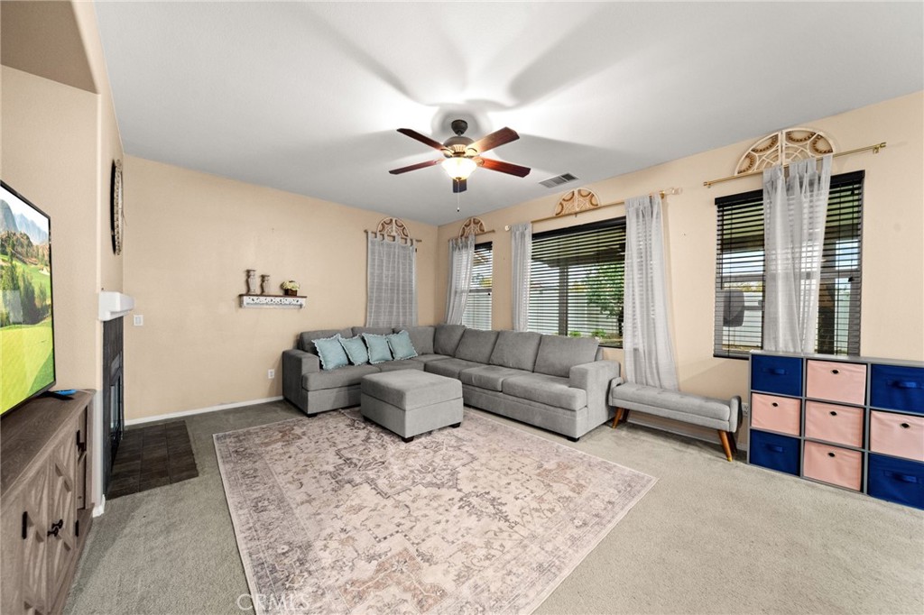 11345 Sanders Street Beaumont, CA 92223 - Photo 19 of 56 a living room with furniture ceiling fan and a flat screen tv