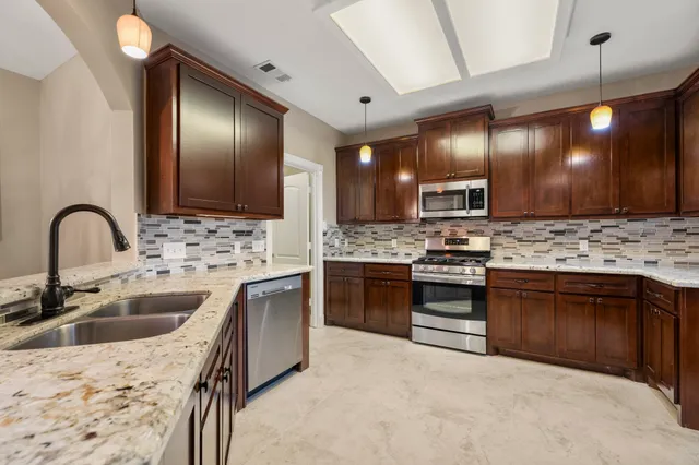a kitchen with stainless steel appliances kitchen island granite countertop a sink stove and refrigerator