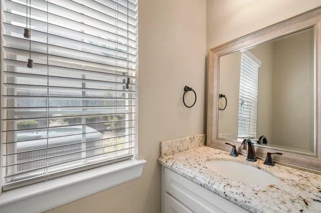 a bathroom with a granite countertop sink and a mirror