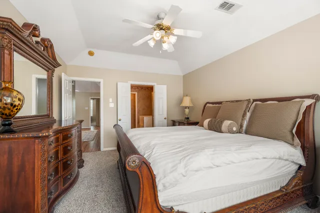 a spacious bedroom with a bed a dresser and potted plants