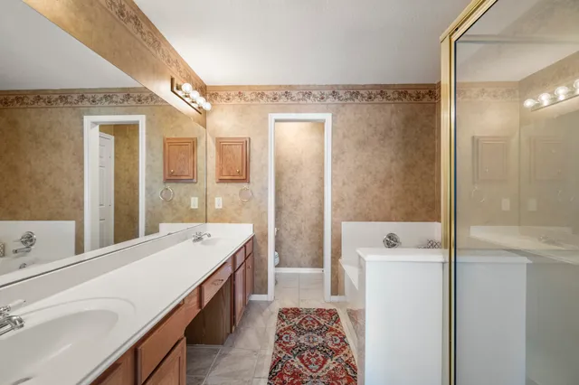 a spacious bathroom with a double vanity sink a mirror and a shower