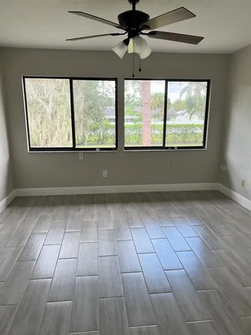 an empty room with windows and a ceiling fan