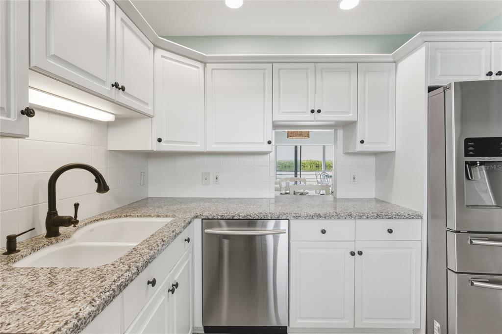 4420 Exeter Drive, Unit 303 Longboat Key, FL 34228 - Photo 18 of 42 a kitchen with granite countertop a sink stainless steel appliances and cabinets