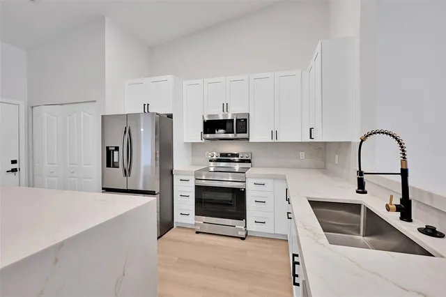 a kitchen with granite countertop a stove a refrigerator and a sink