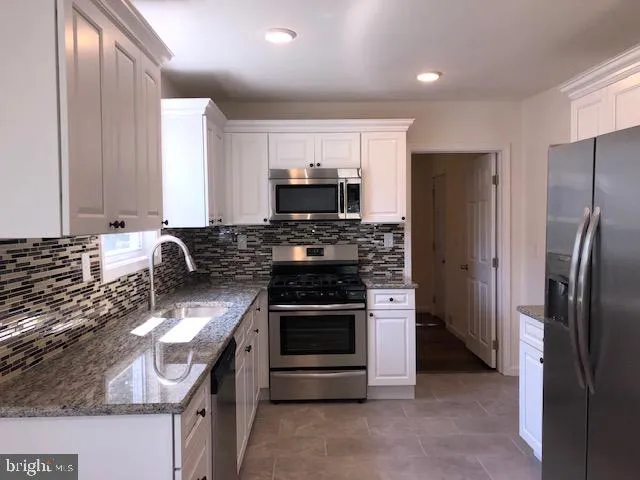 a kitchen with stainless steel appliances granite countertop a stove a refrigerator and a sink