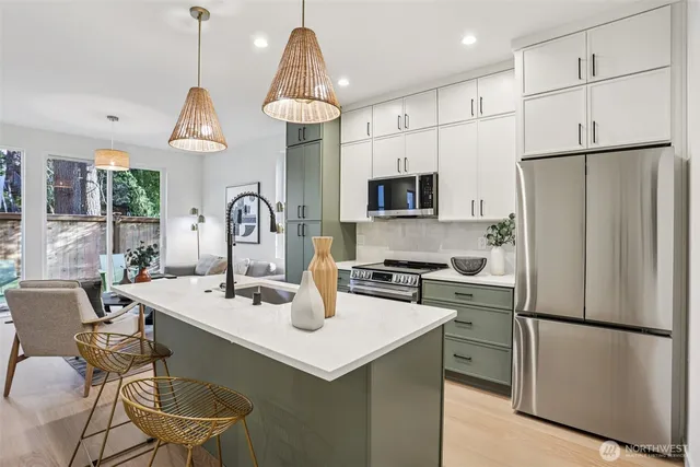 a kitchen with stainless steel appliances a refrigerator a sink a stove a dining table and chairs