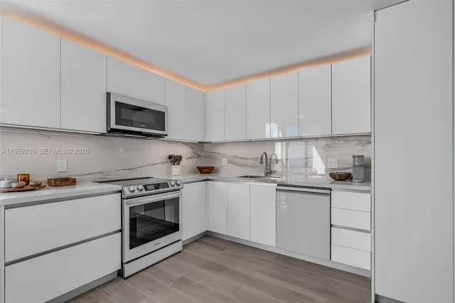 a kitchen with stainless steel appliances granite countertop a sink a stove a microwave and cabinets