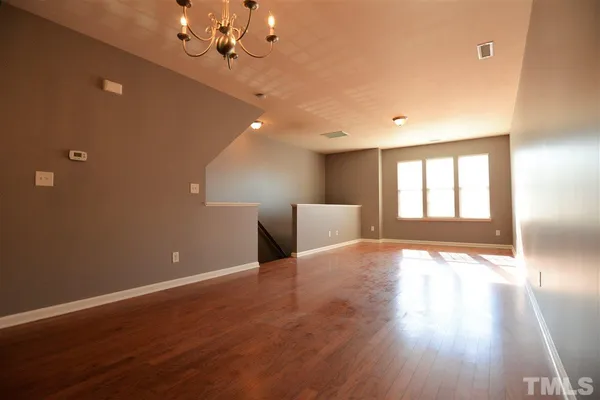 a view of an empty room with window and wooden floor