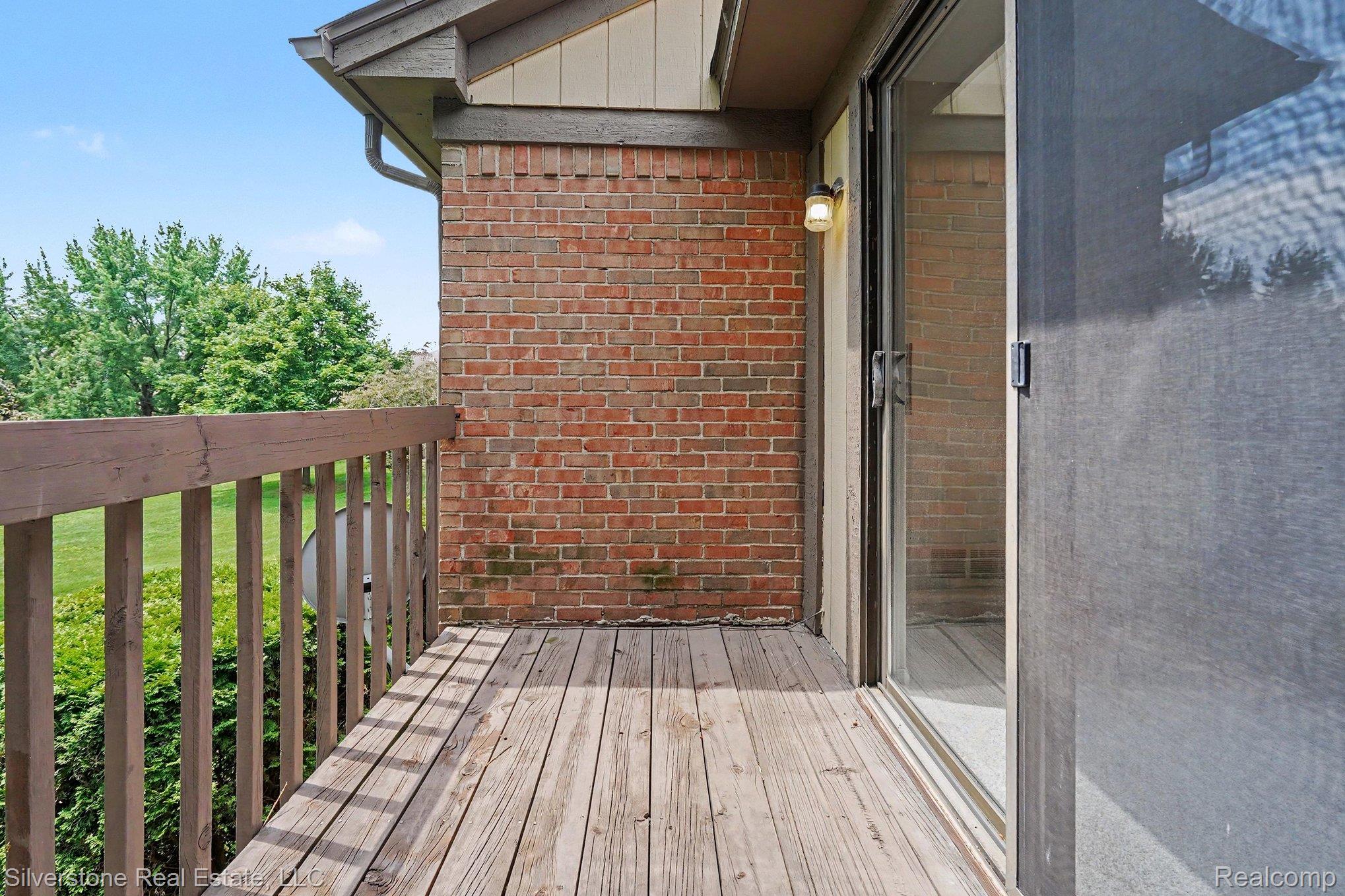 1502 Meadowside Drive Rochester, MI 48307 - Photo 24 of 27 Exterior wood deck featuring a wooden railing, brick wall, and a sliding glass door with a screen