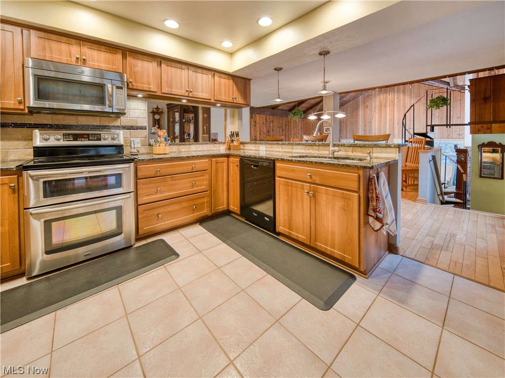 9696 Thwing Road Chardon, OH 44024 - Photo 11 of 35 Kitchen with light hardwood / wood-style floors, decorative light fixtures, appliances with stainless steel finishes, light stone countertops, and backsplash