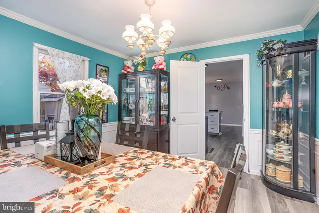a dining room with chandelier and wooden floor