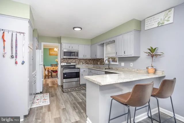 a kitchen with stainless steel appliances granite countertop a stove top oven a sink dishwasher and a refrigerator with wooden floor