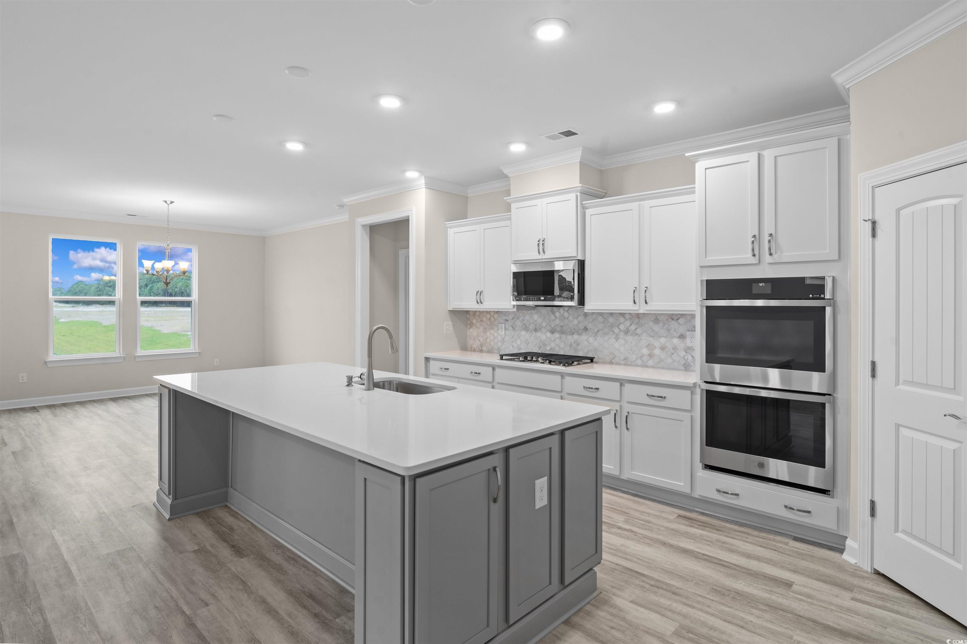 1906 Woodrush Loop Little River, SC 29566 - Photo 15 of 40 Kitchen with stainless steel appliances, white cabinets, light wood-type flooring, sink, and tasteful backsplash