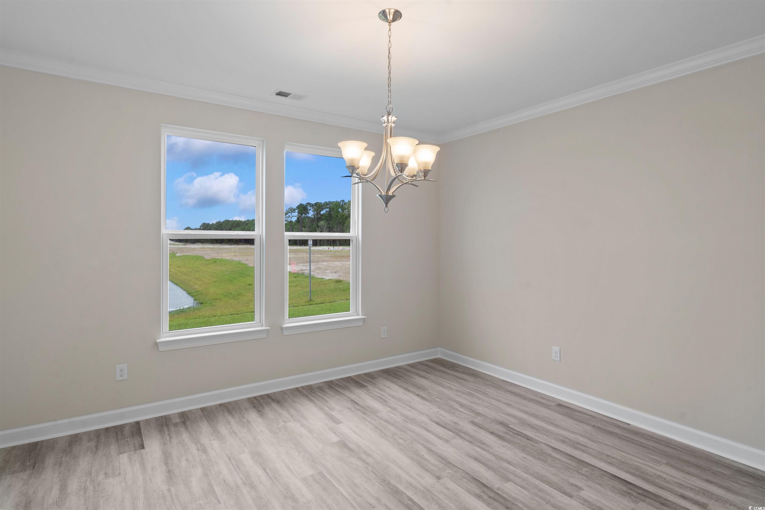 1906 Woodrush Loop Little River, SC 29566 - Photo 17 of 40 Spare room with an inviting chandelier, ornamental molding, hardwood / wood-style flooring, and a wealth of natural light