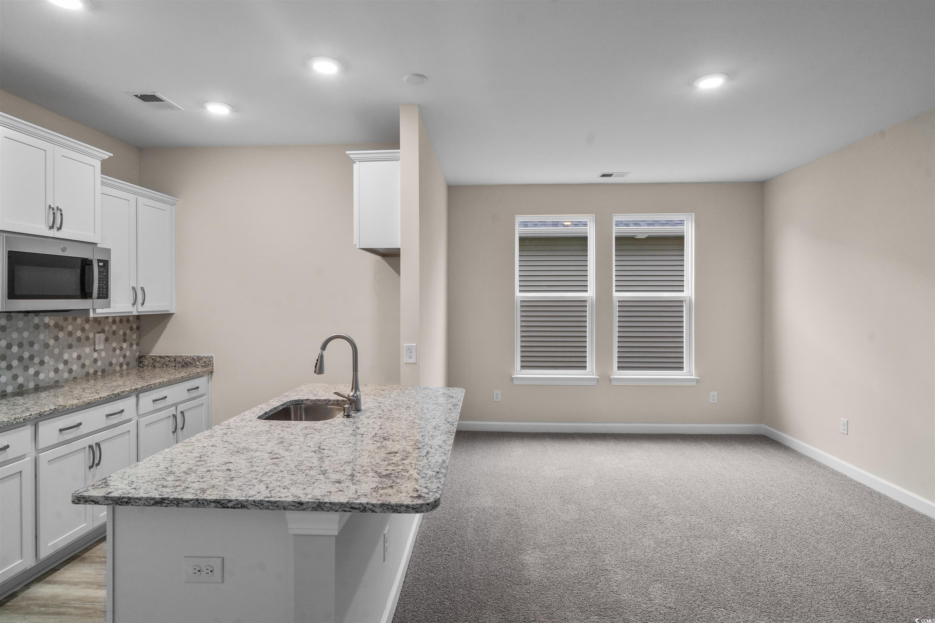 1906 Woodrush Loop Little River, SC 29566 - Photo 5 of 40 Kitchen with white cabinetry, light stone countertops, sink, decorative backsplash, and light colored carpet