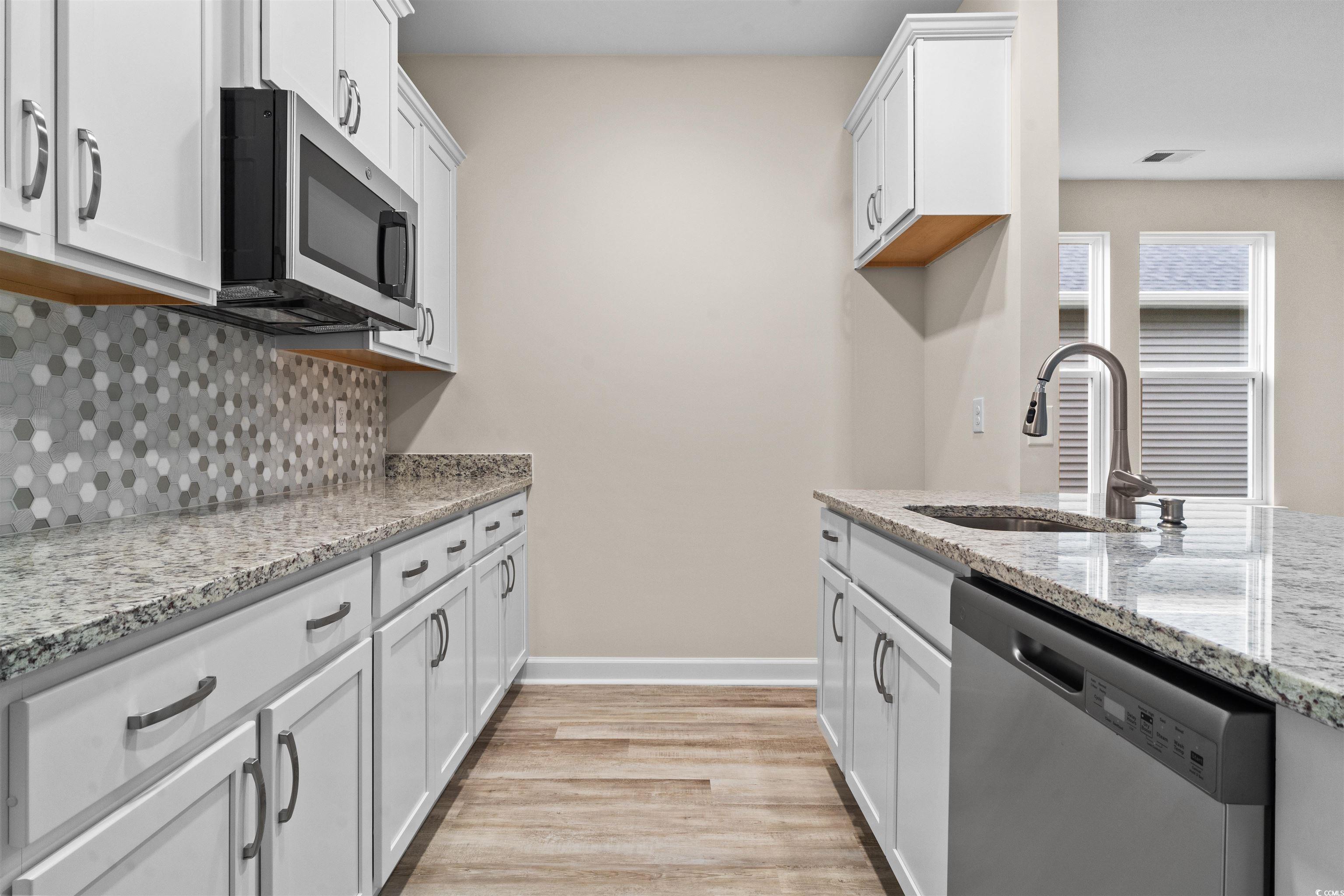 1906 Woodrush Loop Little River, SC 29566 - Photo 8 of 40 Kitchen with decorative backsplash, light stone counters, light hardwood / wood-style floors, stainless steel appliances, and sink