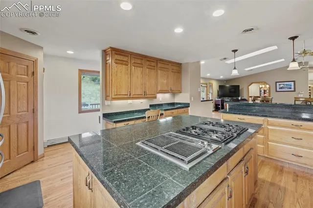 a kitchen with stainless steel appliances granite countertop a stove top oven a sink dishwasher and cabinets with wooden floor
