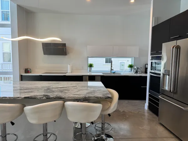 a kitchen with stainless steel appliances granite countertop a sink a stove a refrigerator a dining table and chairs