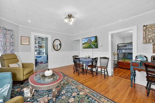 a living room with furniture and a dining table with wooden floor