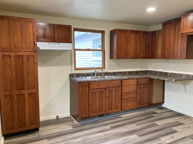 a kitchen with granite countertop wooden cabinets a sink and a window
