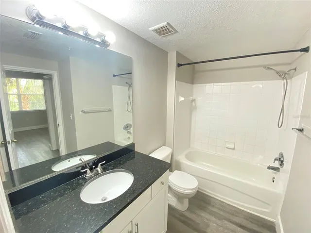 a bathroom with a granite countertop sink toilet a shower and a mirror