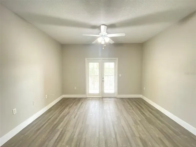 an empty room with wooden floor fan and windows