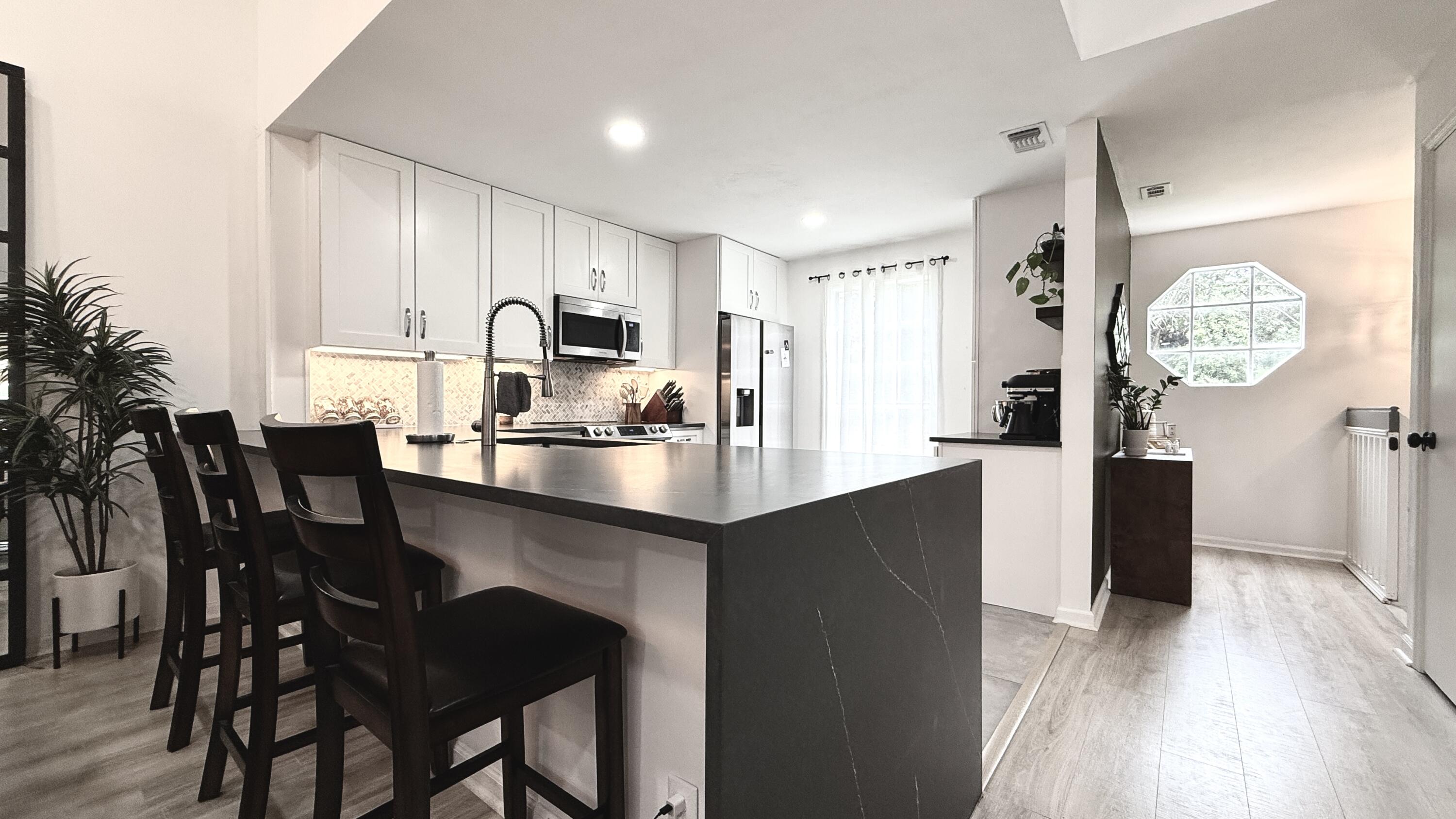 5016 Heatherhill Lane, Unit 10 Boca Raton, FL 33486 - Photo 3 of 12 a kitchen with a table chairs refrigerator and cabinets