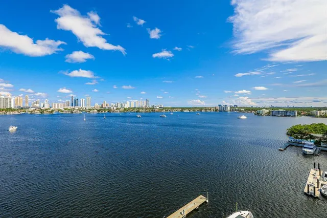 a view of a lake with lawn chairs and large trees
