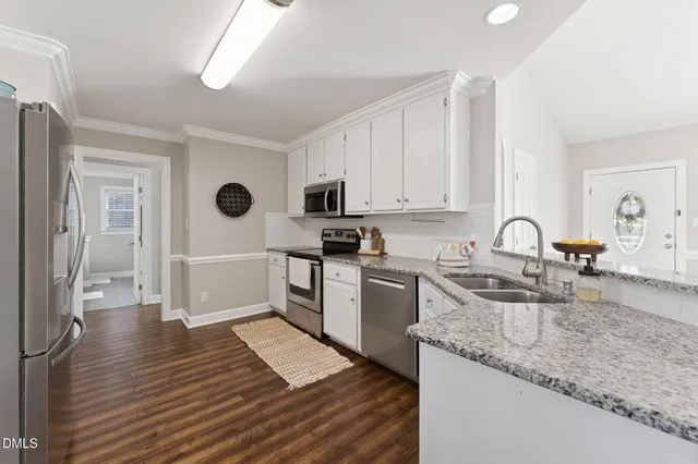 a kitchen with granite countertop a sink cabinets and stainless steel appliances