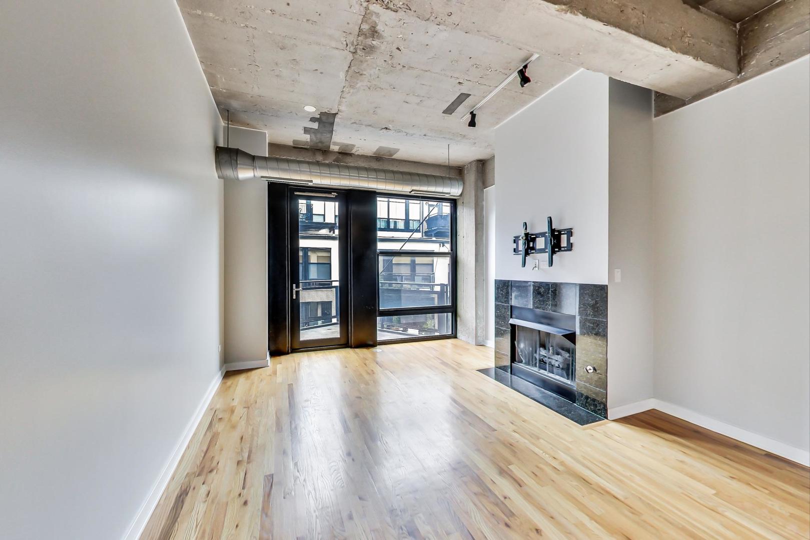 1069 West 14th Place, Unit 310 Chicago, IL 60608 - Photo 4 of 25 a view of an empty room with a window and wooden floor