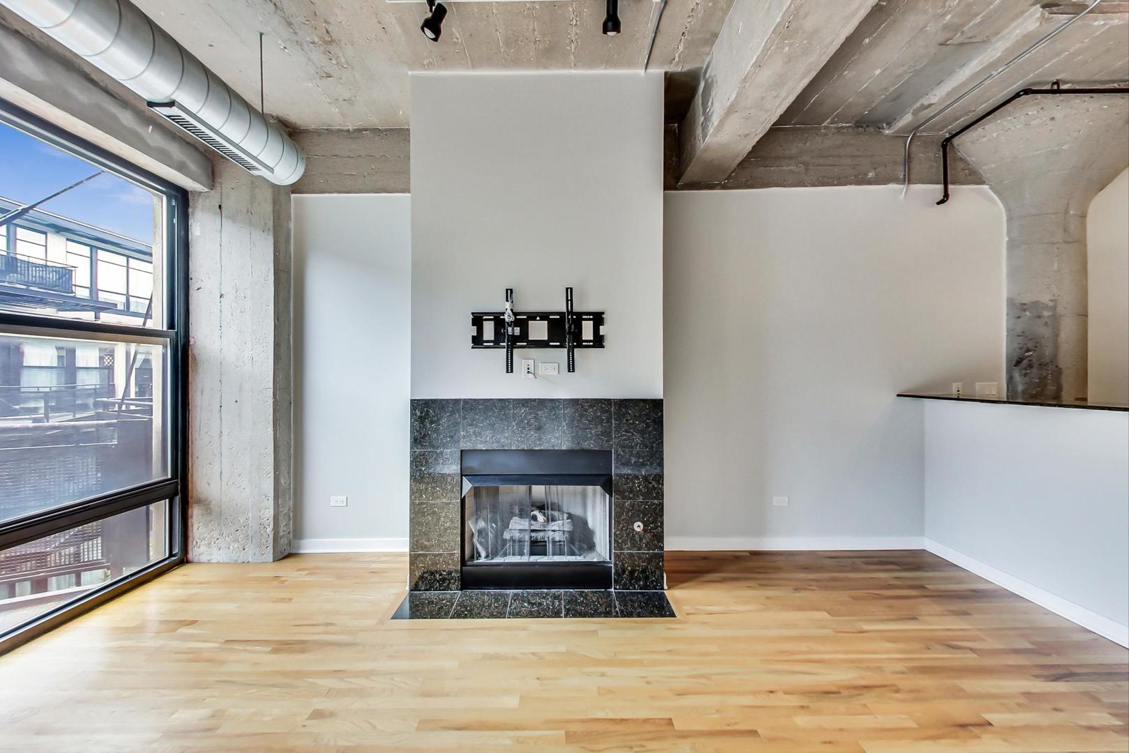 1069 West 14th Place, Unit 310 Chicago, IL 60608 - Photo 5 of 25 a view of an empty room with wooden floor and a window