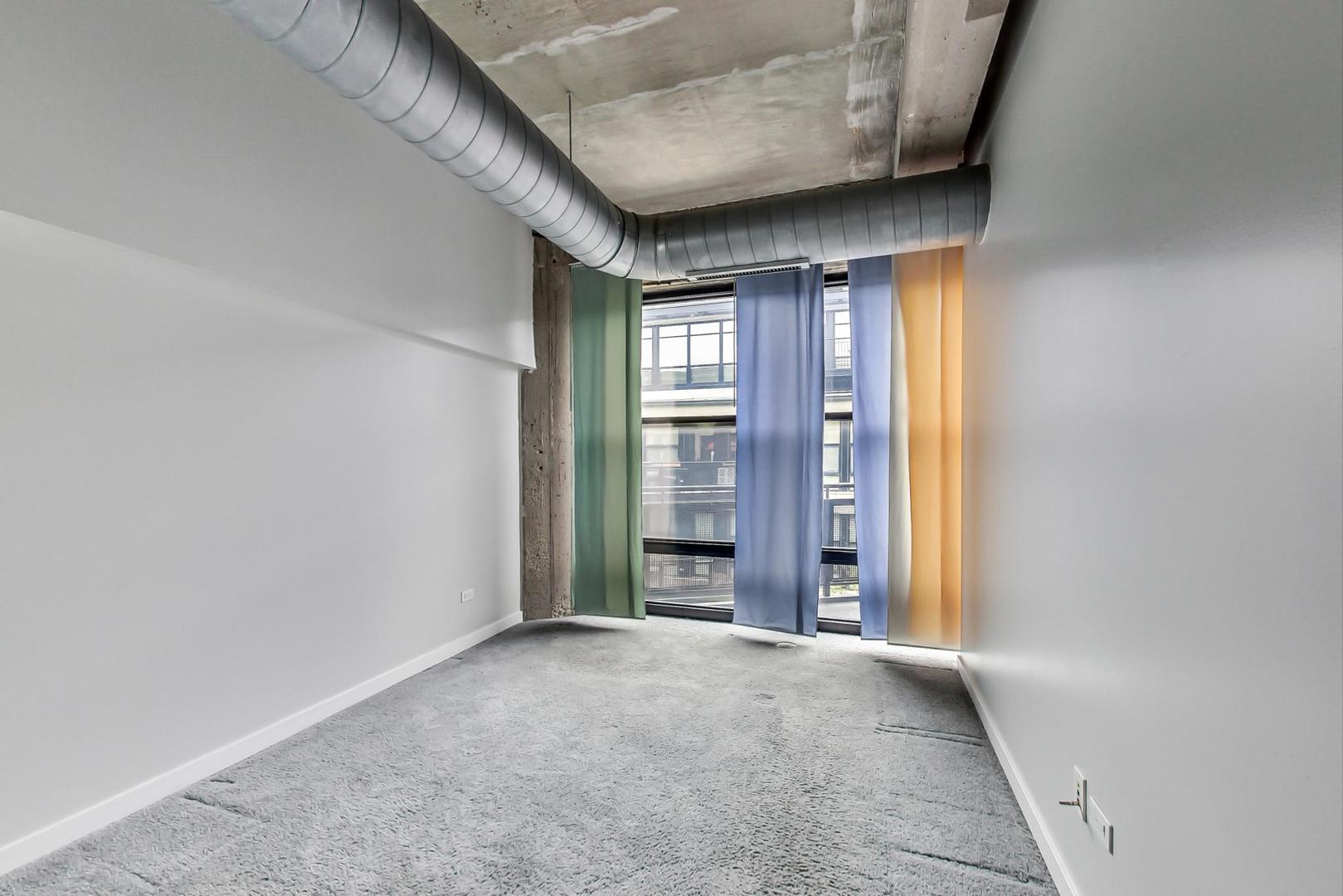 1069 West 14th Place, Unit 310 Chicago, IL 60608 - Photo 10 of 25 a view of an empty room with a fireplace and a window
