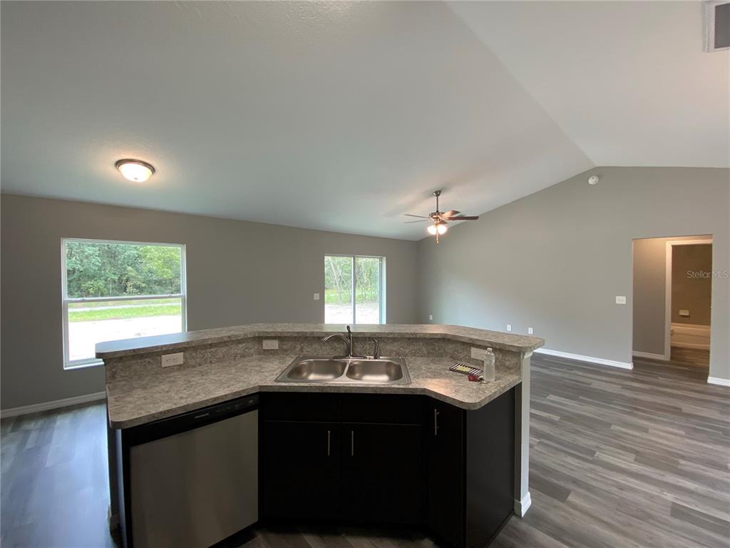 15945 Southwest 57th Terrace Road Ocala, FL 34473 - Photo 11 of 24 a sink with granite countertop a sink dishwasher a stove and a refrigerator with wooden floor