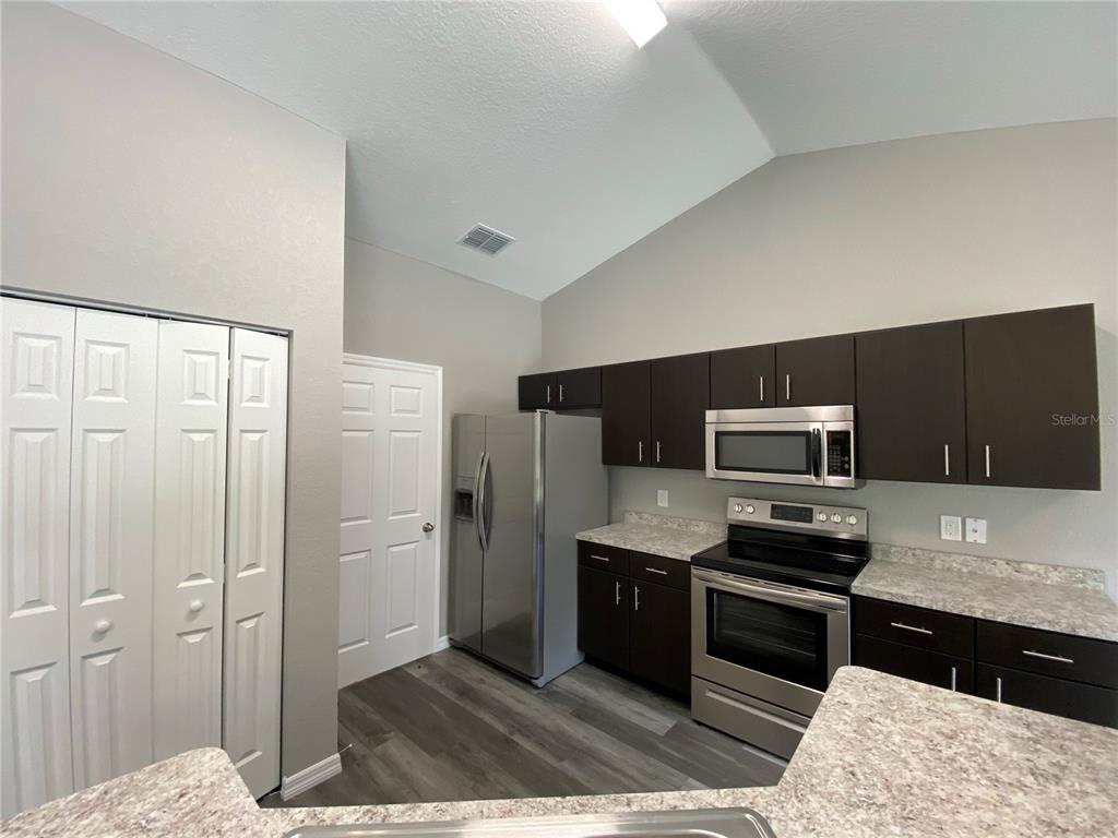 15945 Southwest 57th Terrace Road Ocala, FL 34473 - Photo 12 of 24 a kitchen with stainless steel appliances kitchen island granite countertop a refrigerator and a sink