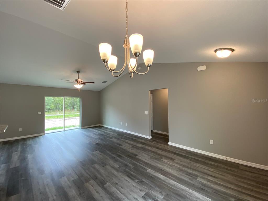15945 Southwest 57th Terrace Road Ocala, FL 34473 - Photo 4 of 24 a view of wooden floor windows and a chandelier fan in an empty room
