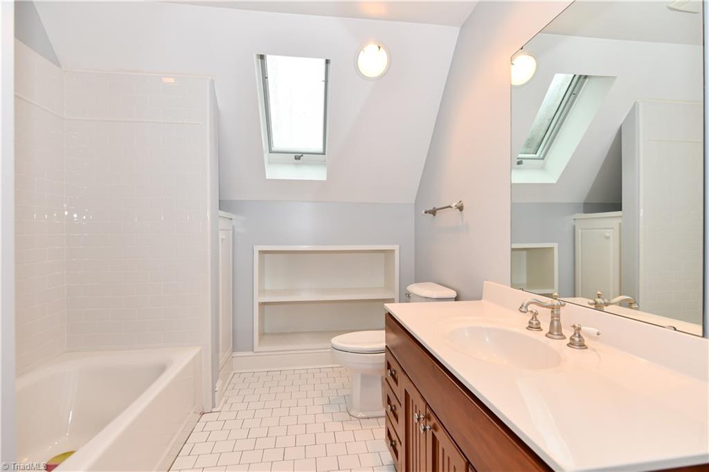 5606 Wallburg-High Point Road High Point, NC 27265 - Photo 15 of 30 The hall full bathroom has tile flooring, built-in cabinetry + shelves, shower/tub combination, single bowl vanity, and a tilt-out with screen skylight.