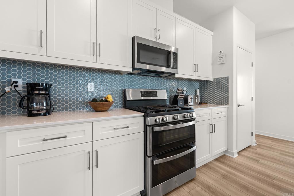 35115 Crop Place Fallbrook, CA 92028 - Photo 12 of 41 a kitchen with stainless steel appliances granite countertop grey cabinets a stove a microwave and a hard wood floors