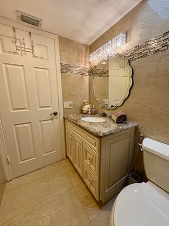 a bathroom with a granite countertop sink a toilet and a mirror