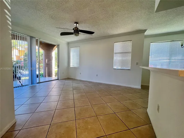a view of an empty room with window and chandelier fan