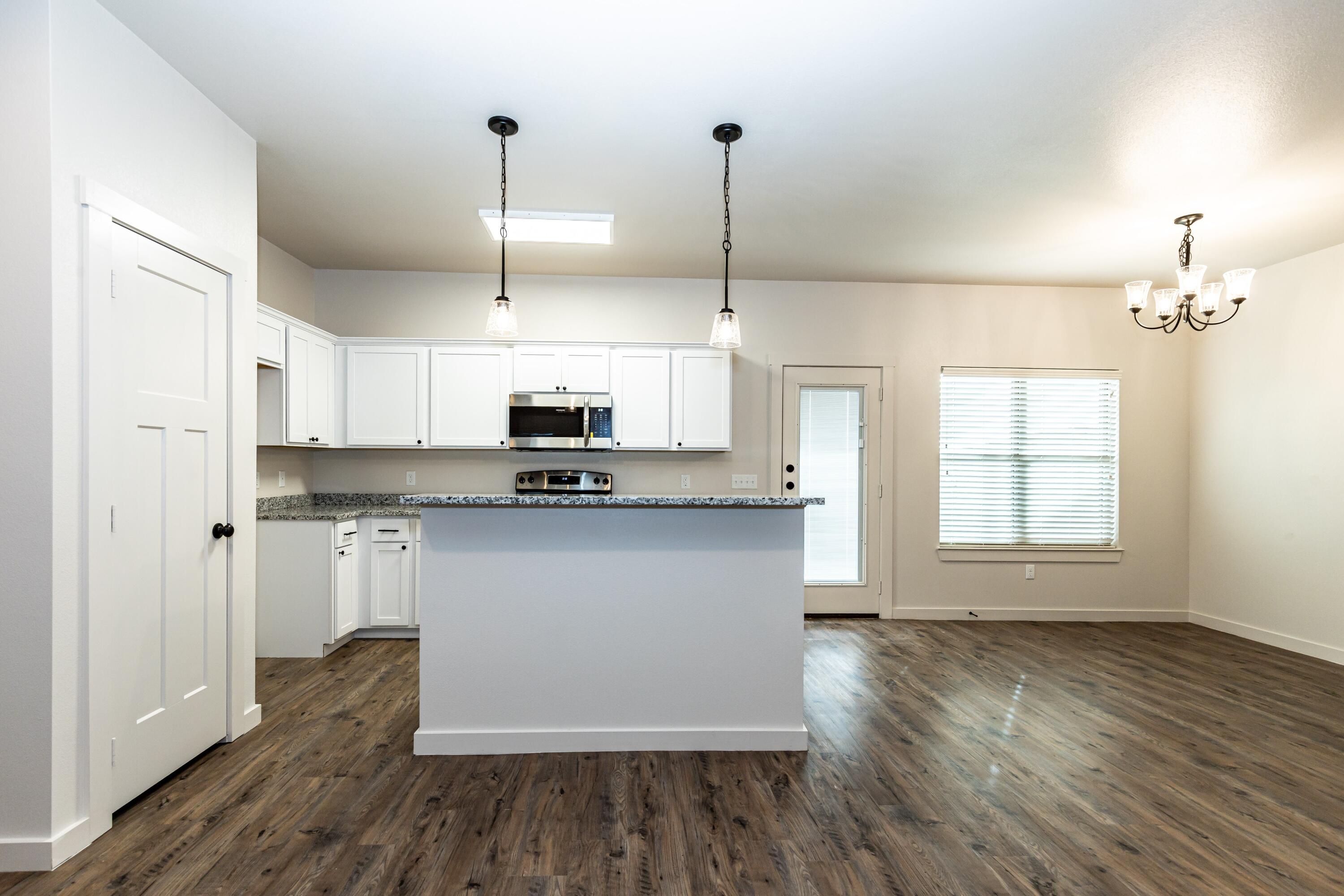 2529 138th Street Lubbock, TX 79423 - Photo 6 of 24 a kitchen with stainless steel appliances granite countertop a refrigerator a sink dishwasher a stove and white countertops with wooden floor