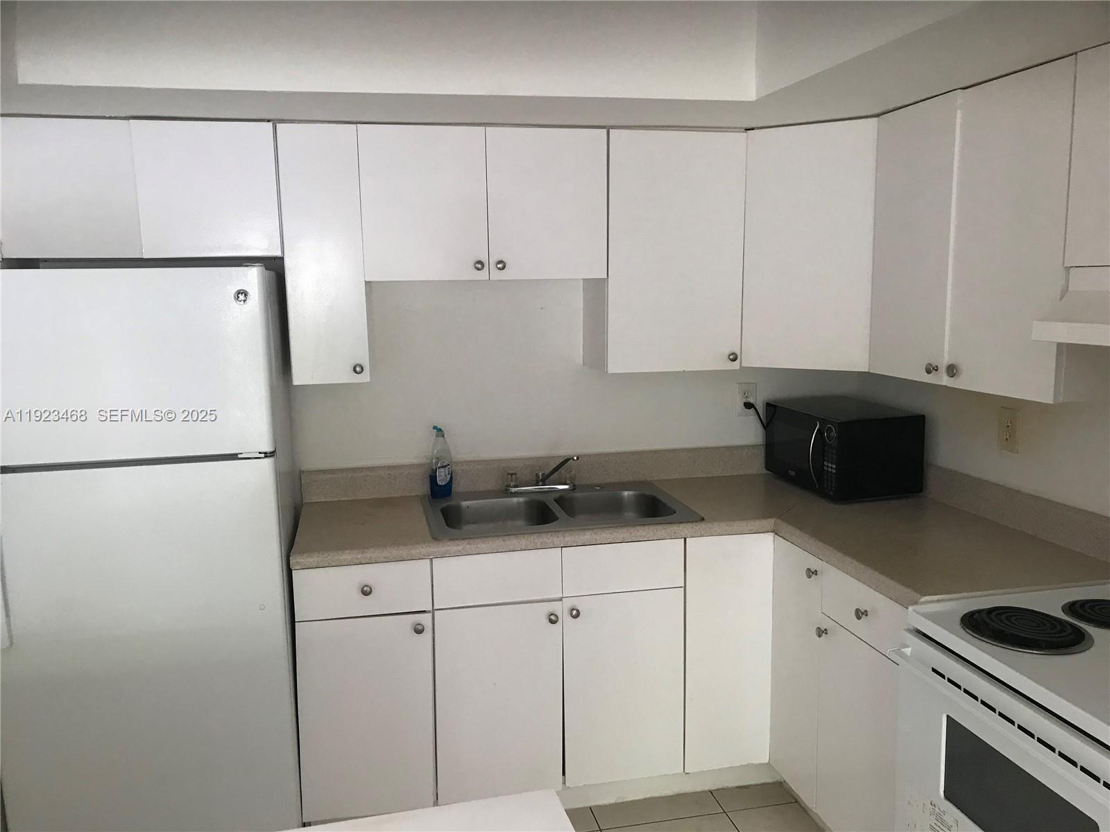 206 Northeast 3rd Street, Unit 10 Hallandale Beach, FL 33009 - Photo 4 of 6 a kitchen with appliances a sink and cabinets