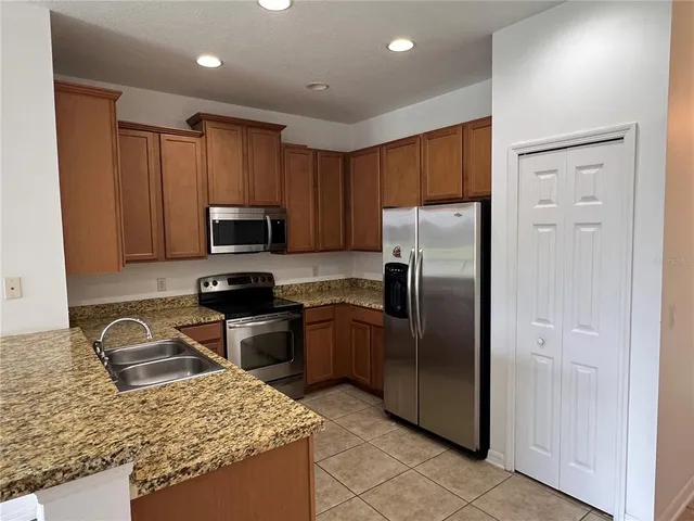 a kitchen with granite countertop stainless steel appliances a refrigerator a stove top oven and granite countertops