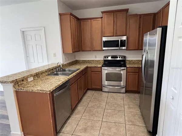 a kitchen with stainless steel appliances granite countertop a stove a sink and a microwave
