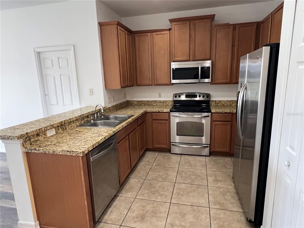 9013 Shepton Street Orlando, FL 32825 - Photo 5 of 20 a kitchen with stainless steel appliances granite countertop a stove a sink and a microwave