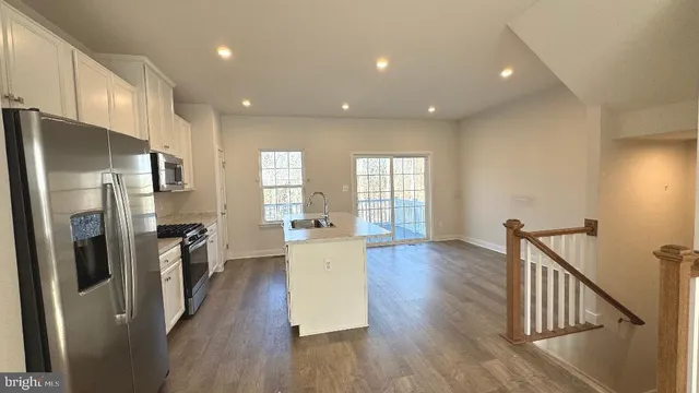 a view of a kitchen with refrigerator and wooden floor