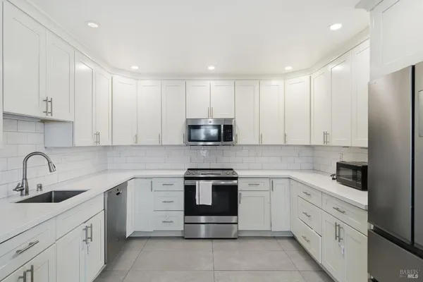 a kitchen with white cabinets stainless steel appliances and sink
