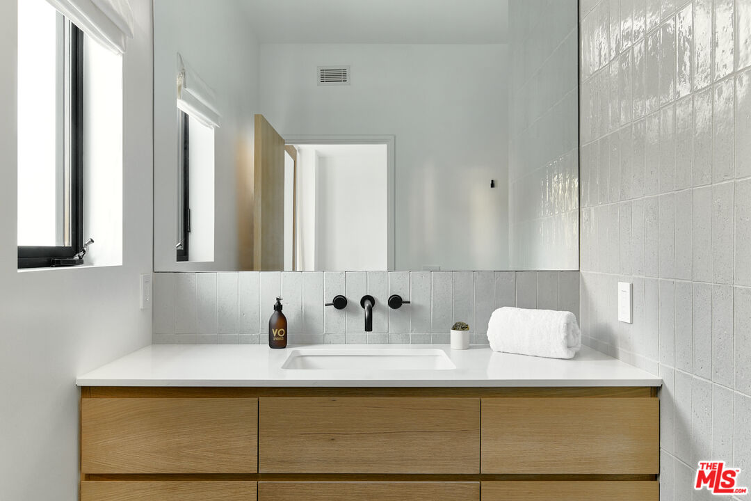 3858 Hayvenhurst Drive Encino, CA 91436 - Photo 35 of 49 a bathroom with a sink and a mirror