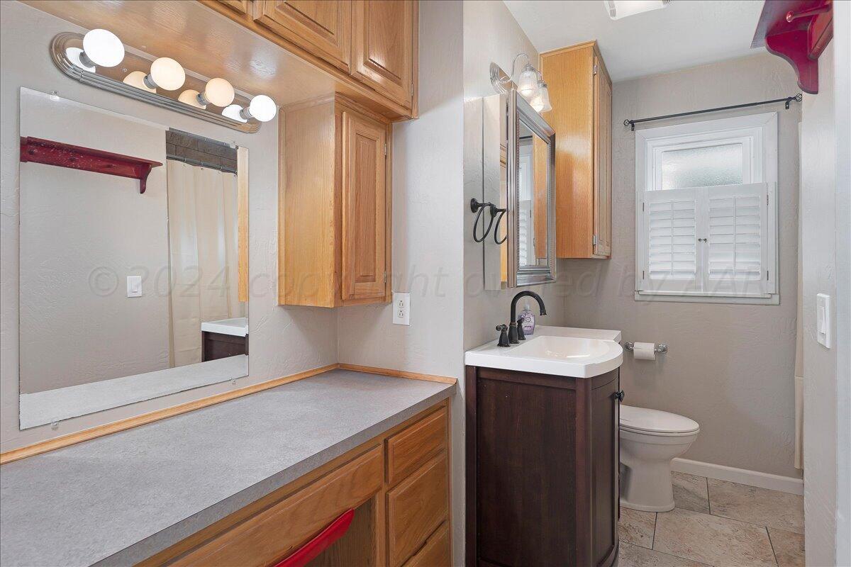 3017 Mockingbird Lane Amarillo, TX 79109 - Photo 20 of 25 a bathroom with a sink a toilet and a mirror